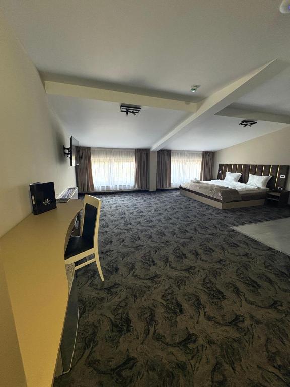 Apartament la mansardă cu tavan înclinat cu grinzi, birou galben cu scaun și pat dublu în fundal.