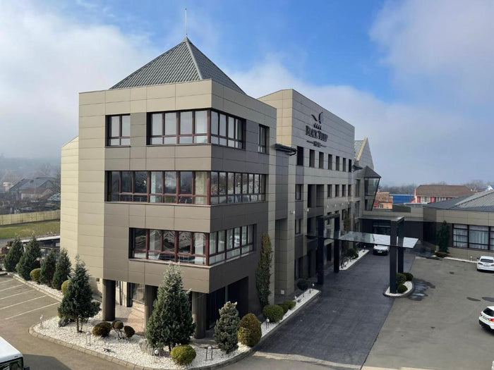 Vedere aeriană a fațadei Black Tulip Hotel Dej într-o dimineață cu ceață, cu brazi decorativi la intrare.
