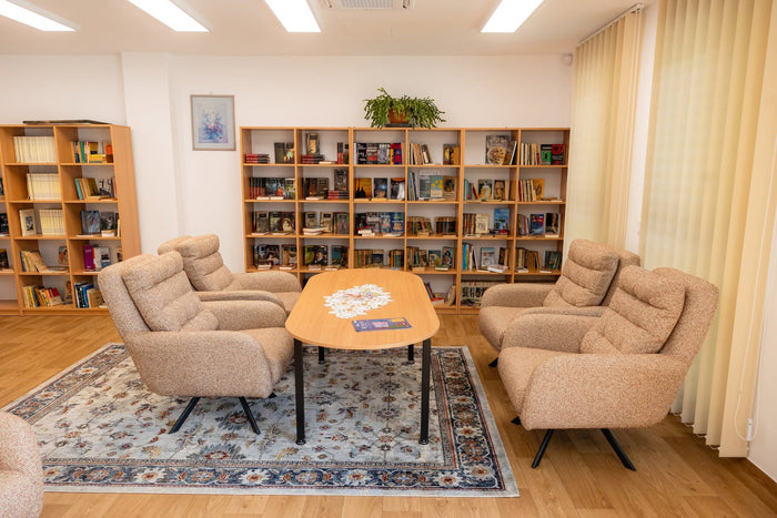 Sala de lectură a Căminului Sfântul Vasile din Cluj-Napoca, cu fotolii pivotante și masă ovală.