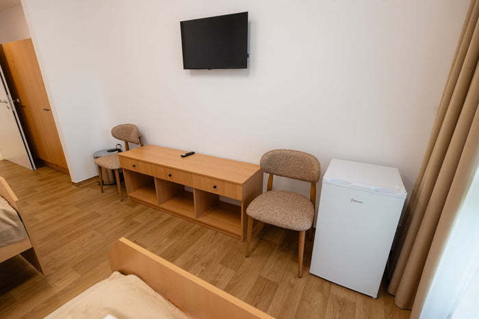 Detaliu de cameră la Căminul Sfântul Vasile Cluj-Napoca, cu mobilier din lemn și scaune tapițate.