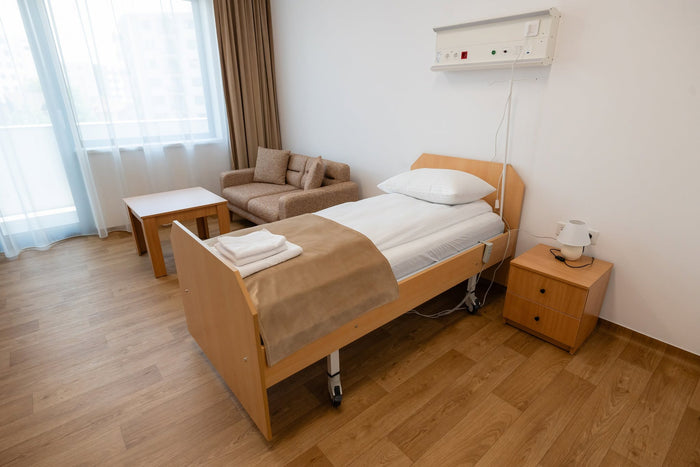 Cameră individuală la Căminul Sfântul Vasile Cluj-Napoca, cu pat de îngrijire, canapea și textile hoteliere.