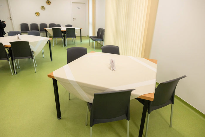 Sala de mese a Căminului Sfântul Vasile din Cluj-Napoca, cu fețe de masă și suporturi pentru șervețele.