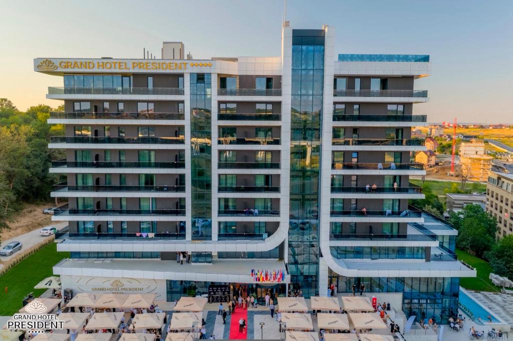 Vedere aeriană a Grand Hotel President la amurg, cu intrarea cu covor roșu, terase și piscină laterală.