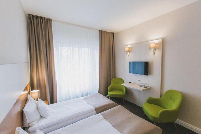 Cameră twin la Hotel Nufărul, cu două fotolii verzi, poliță de perete și televizor între două aplice.