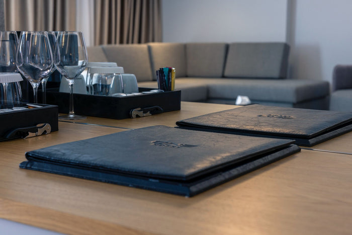 Mape de meniu personalizate cu sigla ONE Hotel, așezate pe masă alături de pahare de vin și tirbușon.