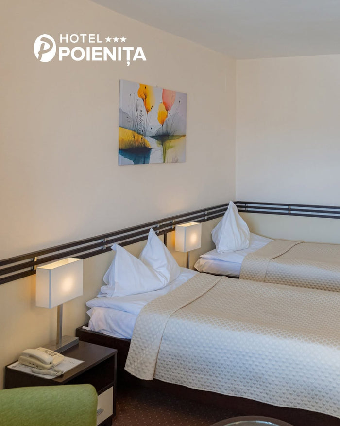 Cameră twin la Hotel Poienița, cu lenjerie albă, cuverturi crem matlasate, veioze pătrate și tablou floral pe perete.