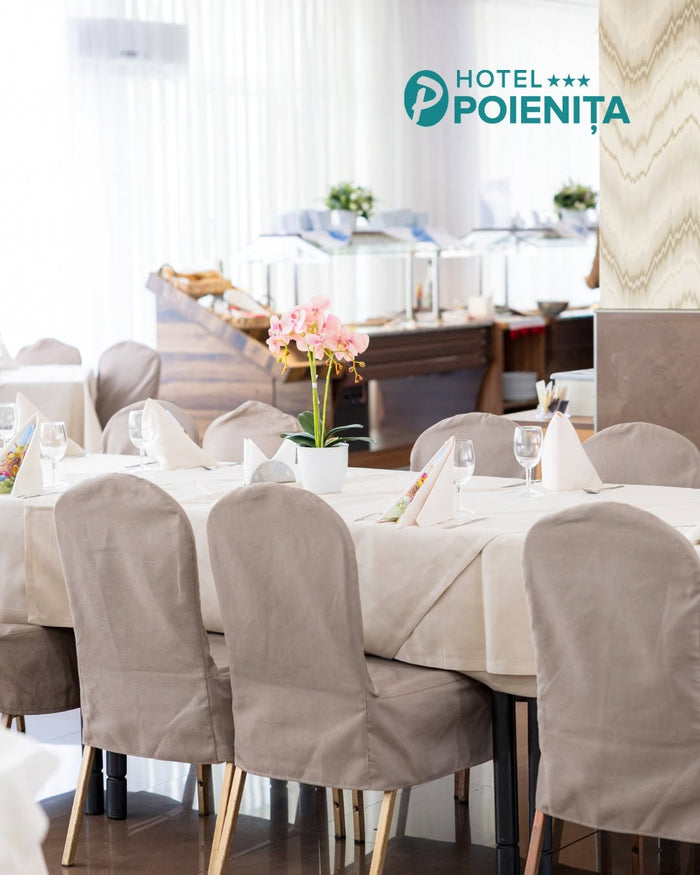 Masă festivă la restaurantul Hotel Poienița, cu huse taupe pe scaune, șervete împăturite și orhidee roz în ghiveci.
