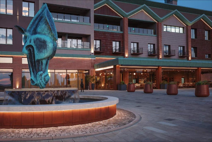 Fațada Issa Resort la amurg, cu o fântână decorativă în formă de cap de cal în prim-plan.