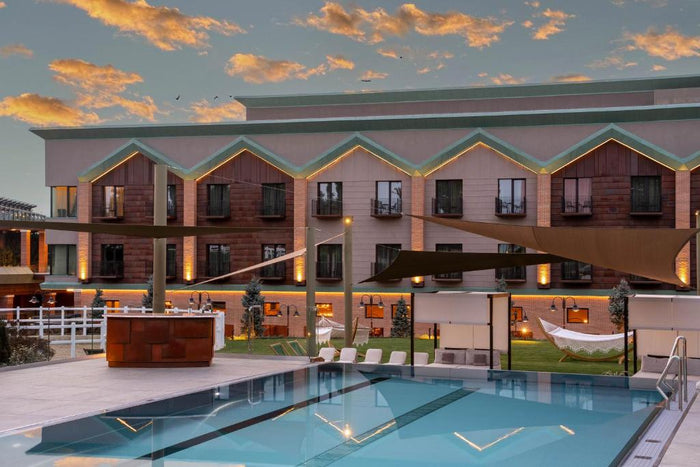 Piscina exterioară a Issa Resort la apus, cu șezlonguri, hamac și clădirea principală în fundal.
