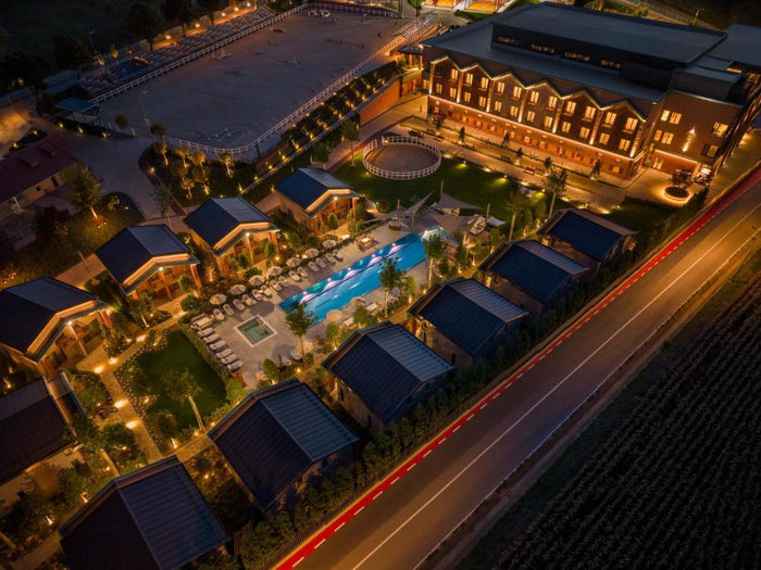 Vedere aeriană nocturnă asupra complexului Issa Resort, cu clădirea principală, căsuțe și piscină.