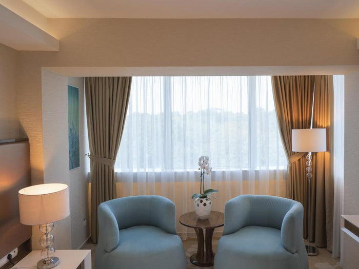 Zonă de relaxare cu două fotolii albastre, o orhidee albă pe măsuța centrală și draperii bej la fereastră.