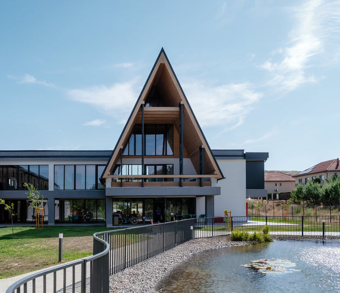 Clădirea Cluj Senior Village văzută dinspre lacul și grădina complexului rezidențial pentru seniori.