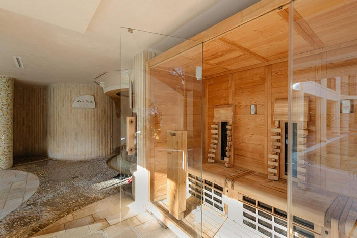 Cabină de saună cu pereți din sticlă, alături de zona Salt Bath cu pardoseală din pietriș și pereți din lemn.